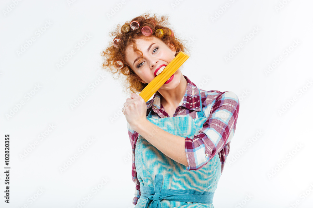 Pretty housewife standing and posing with uncooked spagetti