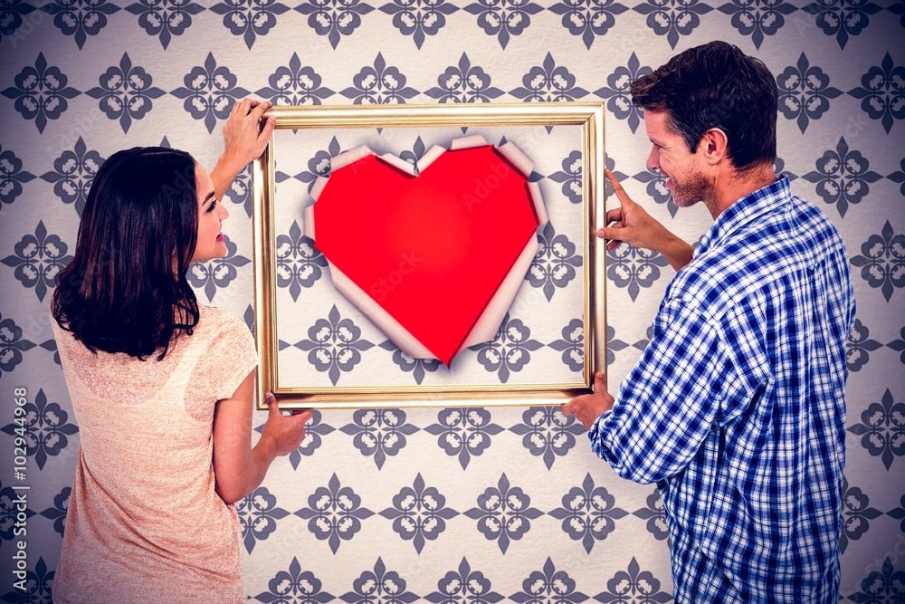 Composite image of happy couple holding picture frame