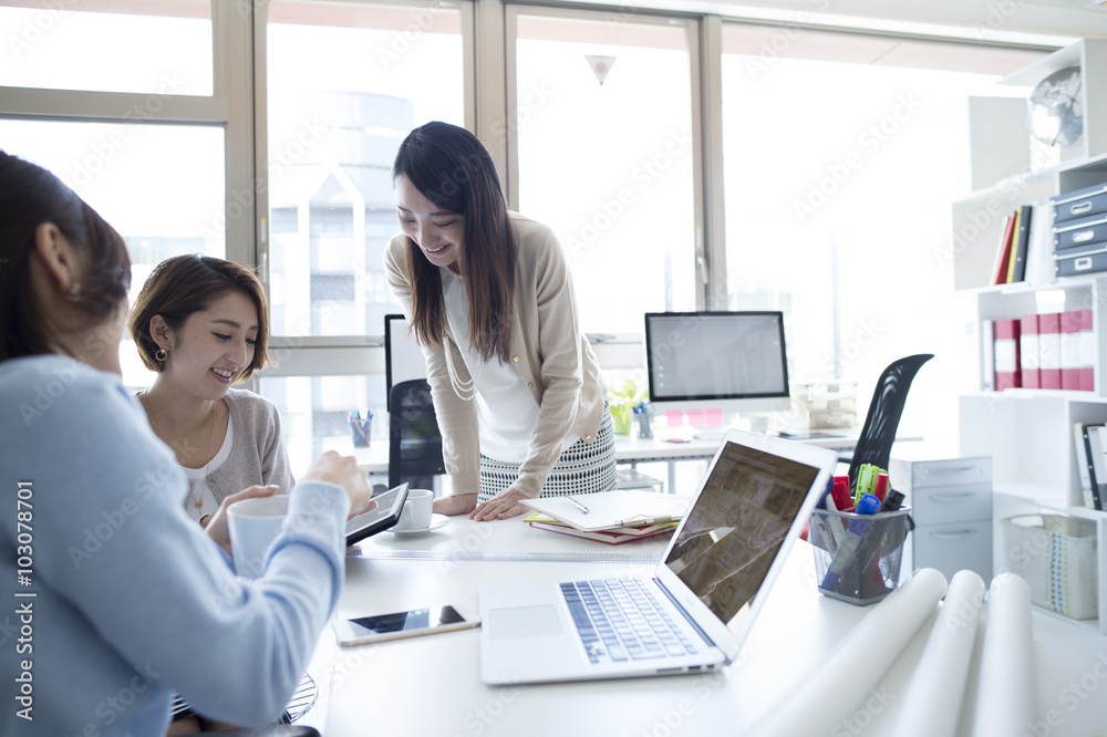 三名女性在办公室里看着平板电脑开会