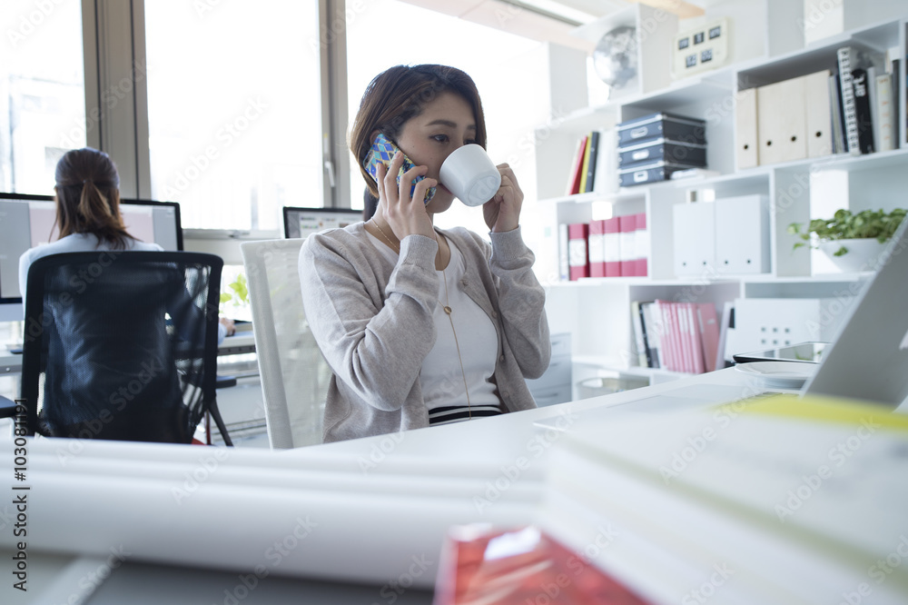 Women are on the phone while drinking coffee in the office