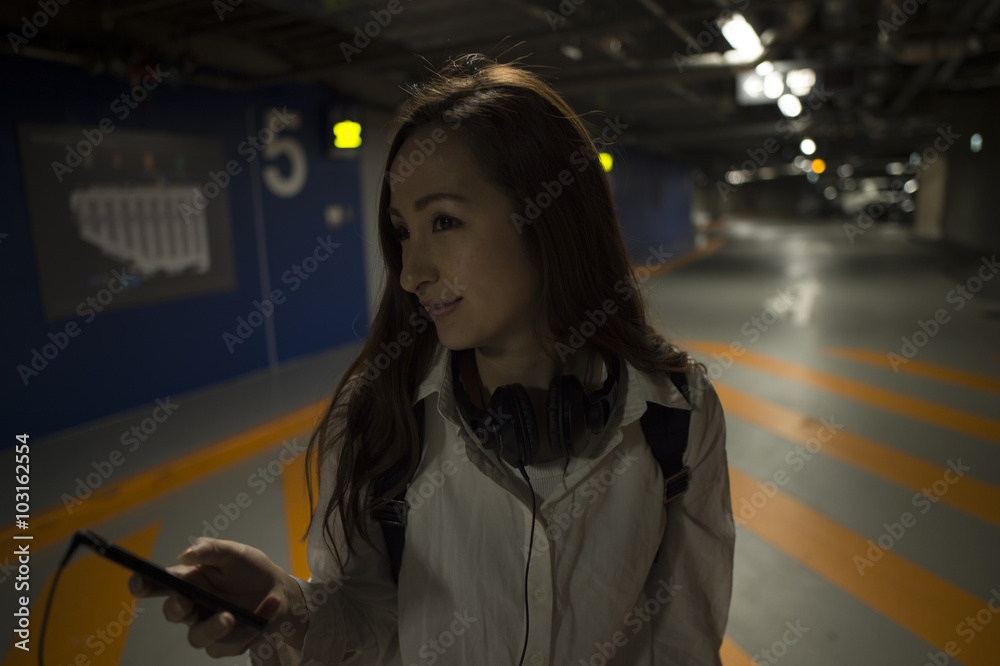 Women are looking at the mobile phone in the basement parking lot