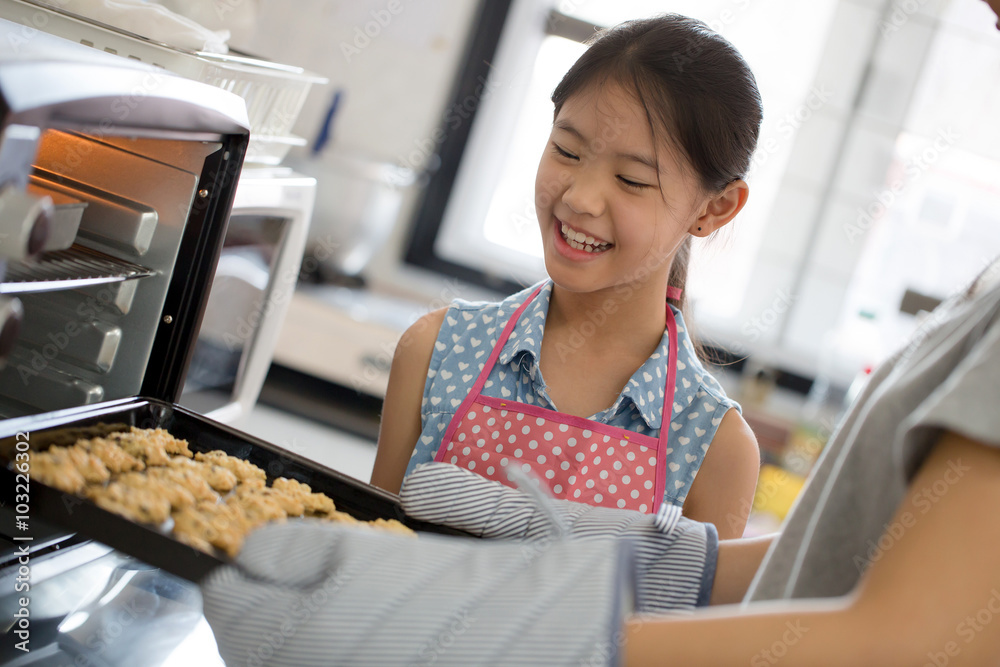 Happy little Asian cute chef looking cookies from oven