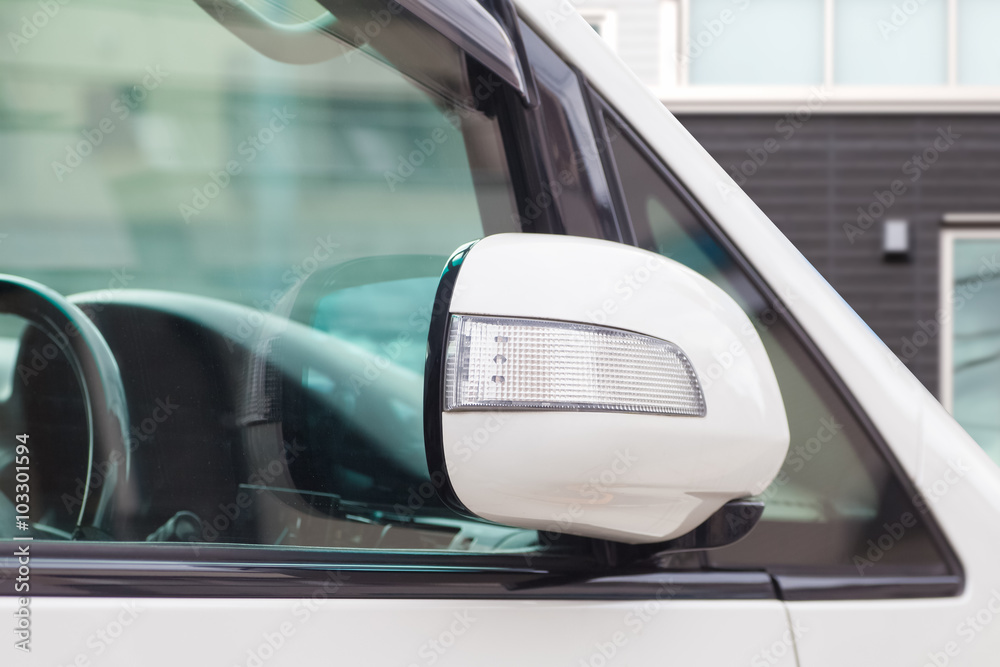 Side rear-view mirror closed for safety at car park.