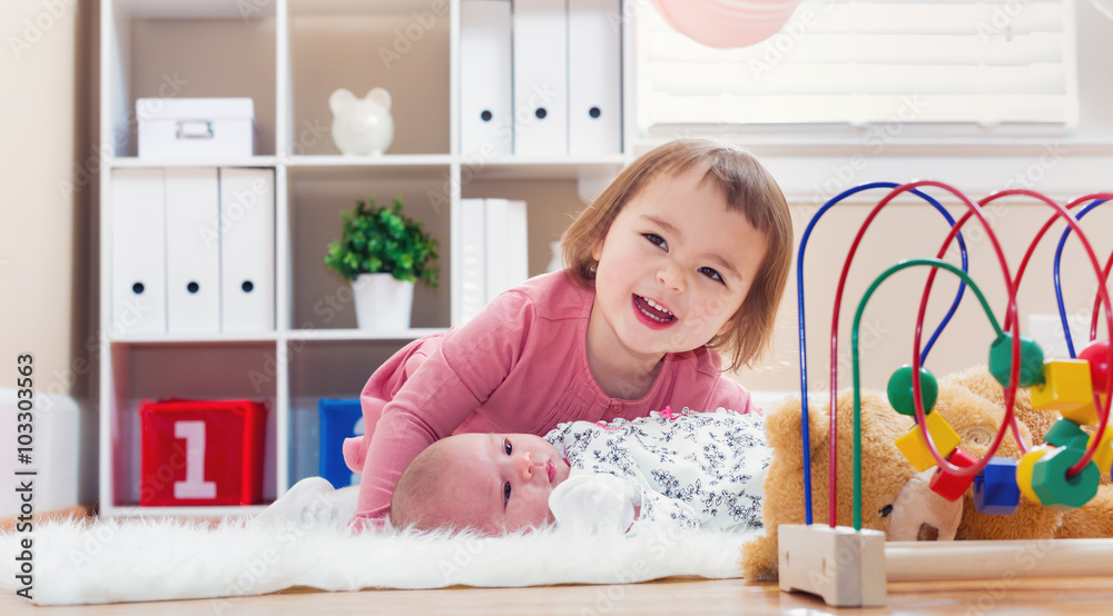 Happy toddler girl playing with her baby sibling