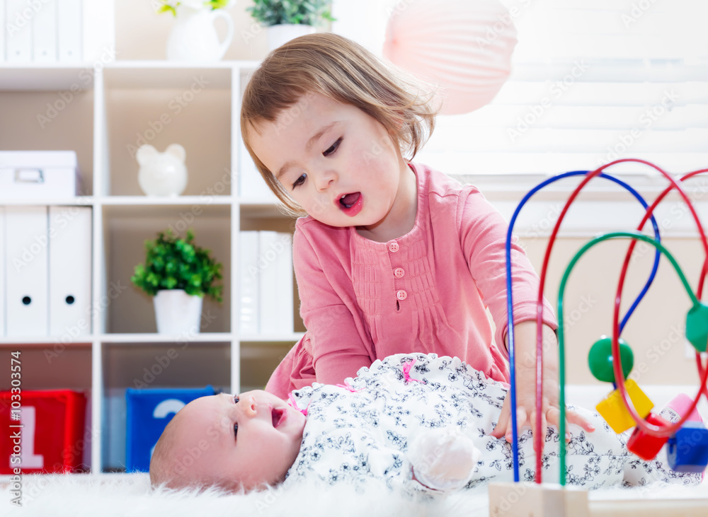 Happy toddler girl playing with her baby sibling