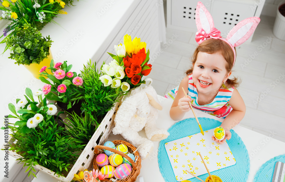  Happy child girl paints eggs for Easter