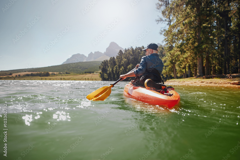 Senior man paddling kayak on a summer day