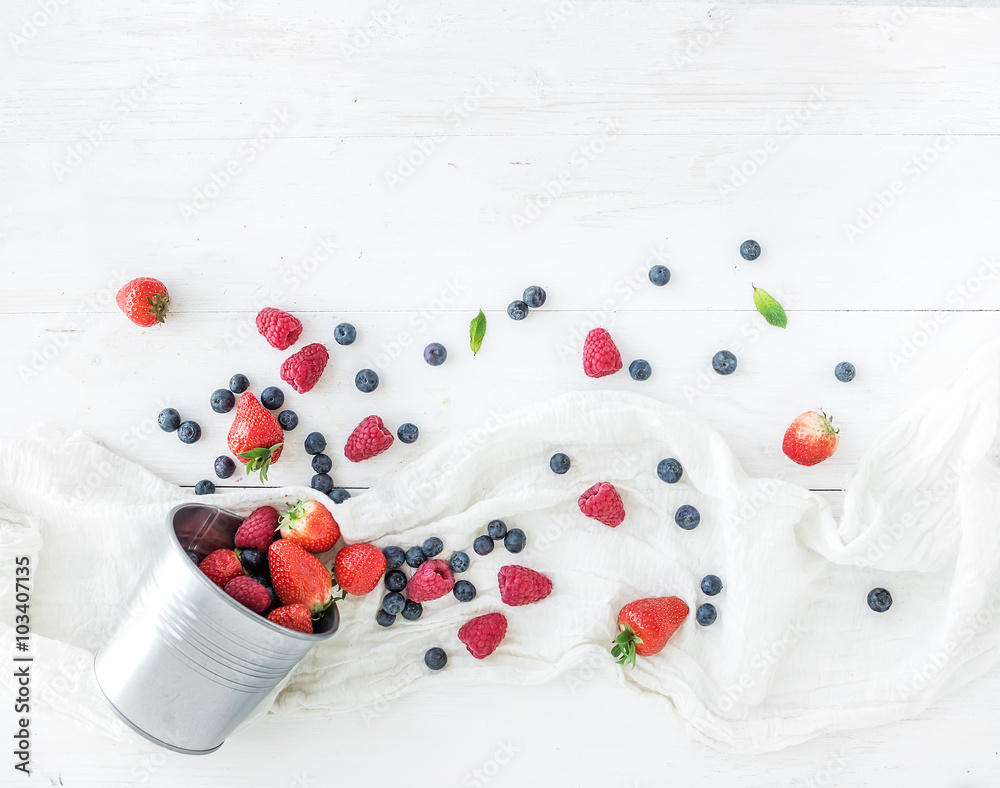 Berry frame with copy space on right. Metal bucket, strawberries, raspberries, blueberries and mint 