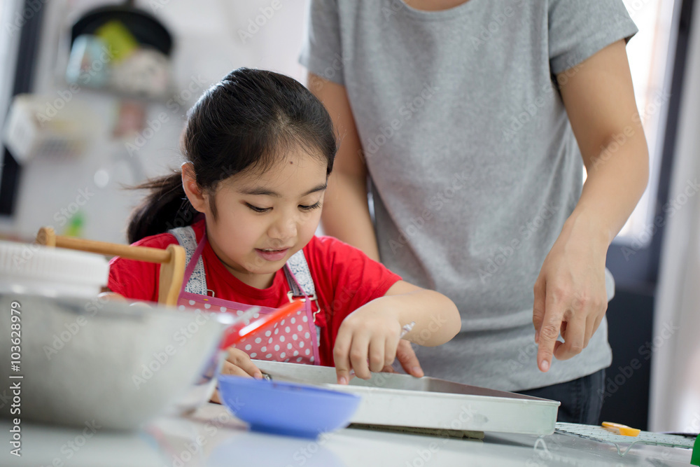 Little Asian cute chef cooking a bakery in kitchen with mother