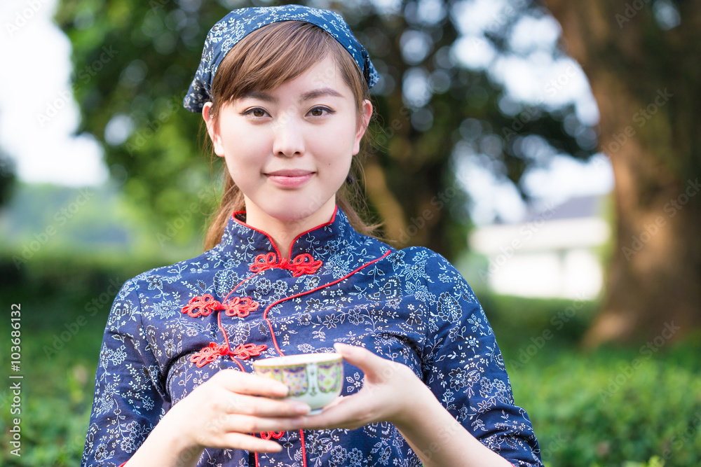 美丽的亚洲女孩在绿茶种植园捧杯