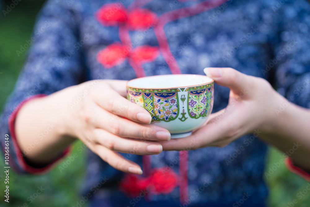 美丽的亚洲女孩在绿茶种植园捧杯