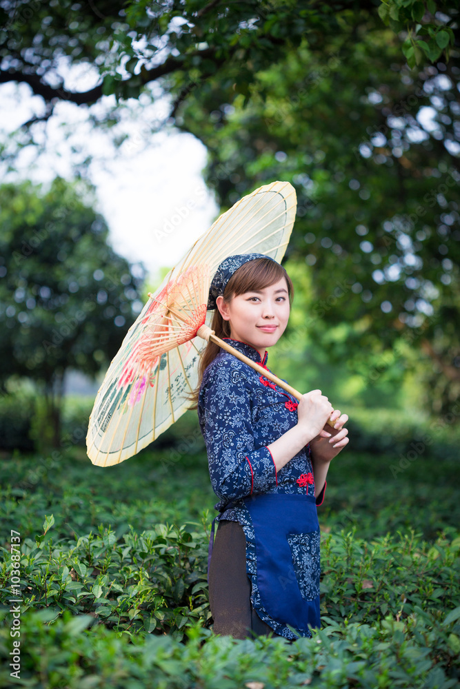 beautiful Asian girl holds umbrella in green tea plantation