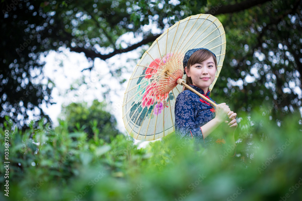 beautiful Asian girl holds umbrella in green tea plantation