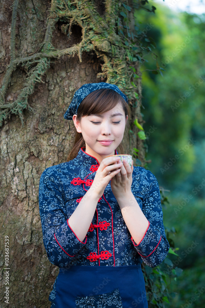 美丽的亚洲女孩在绿茶种植园捧杯