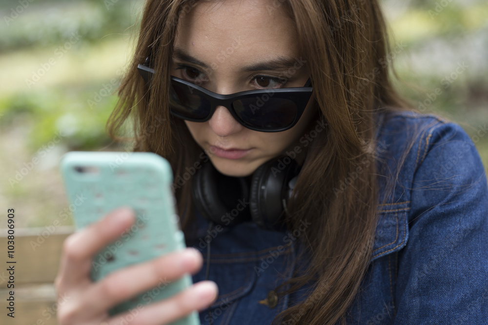 若い女性はサングラスをずらして携帯電話を見ている