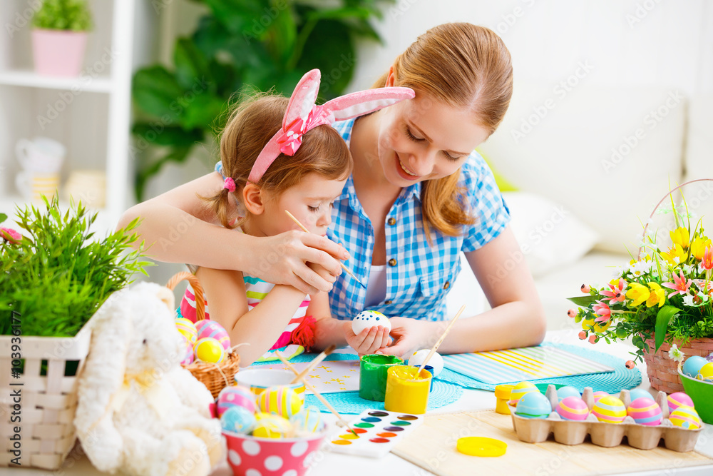 happy family mother and child girl paints eggs for Easter