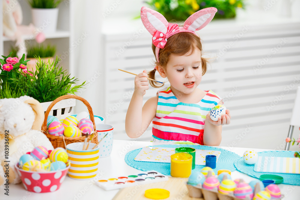  Happy child girl paints eggs for Easter