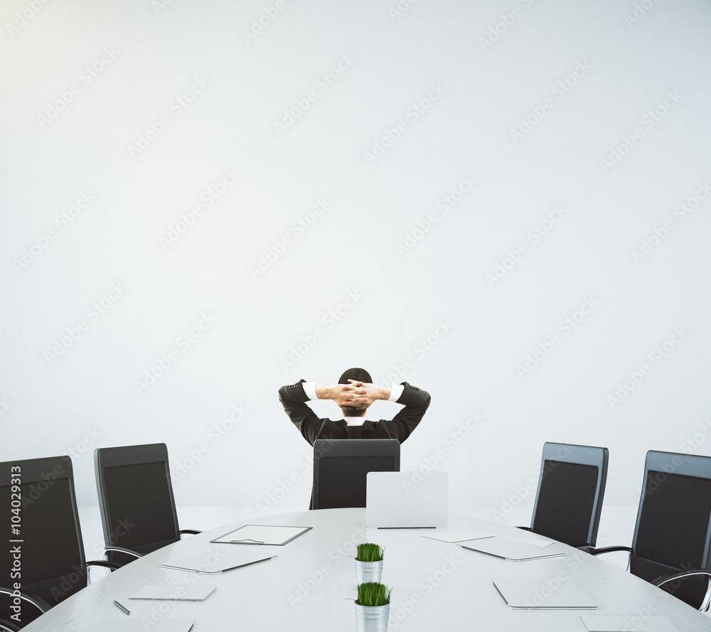 Businessman resting on the chair in conference room with oval ta