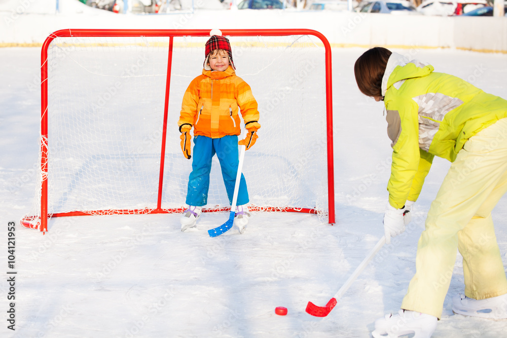 Mother play ice hockey with son outside