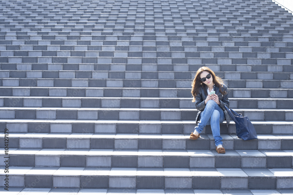 Young woman with sunglasses is sitting on the stairs