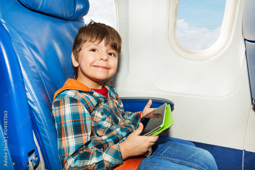 Little boy with tablet pc in airplane chair