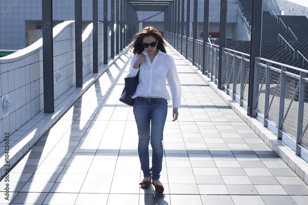 Young woman with sunglasses is walking the overpass