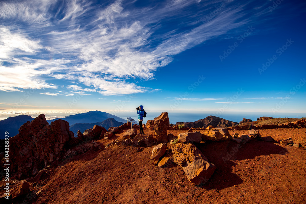 Woman in blue jacket and backpack traveling mountains near Andenes viewpoint on La Palmas island hi