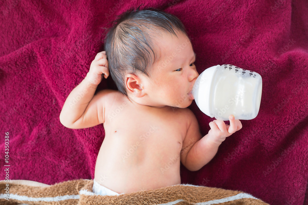 Newborn baby infant eating milk from bottle.