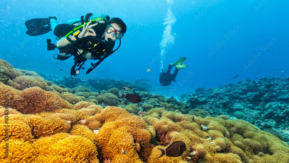 Scuba diver explore a coral reef showing ok sign