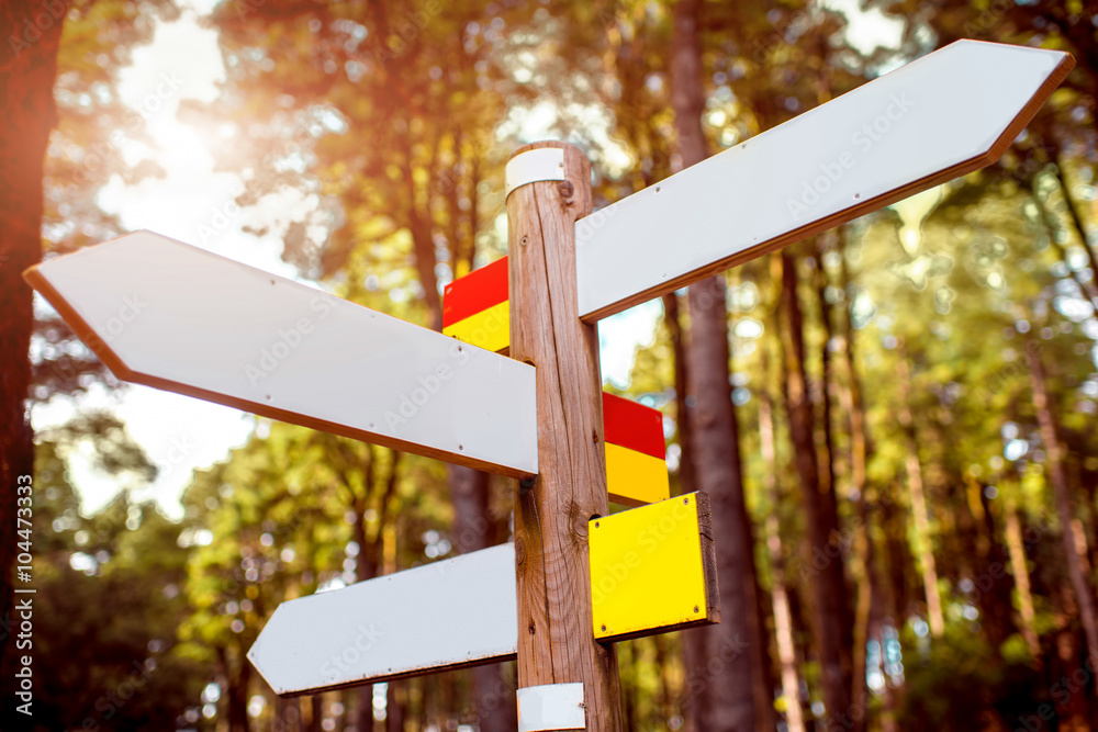 Direction wooden road sign with white tables in the forest