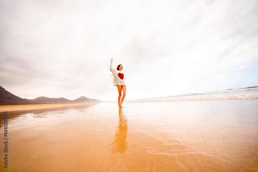 Young woman in sweater having fun enjoying beautiful sandy beach on the foggy weather on Fuerteventu