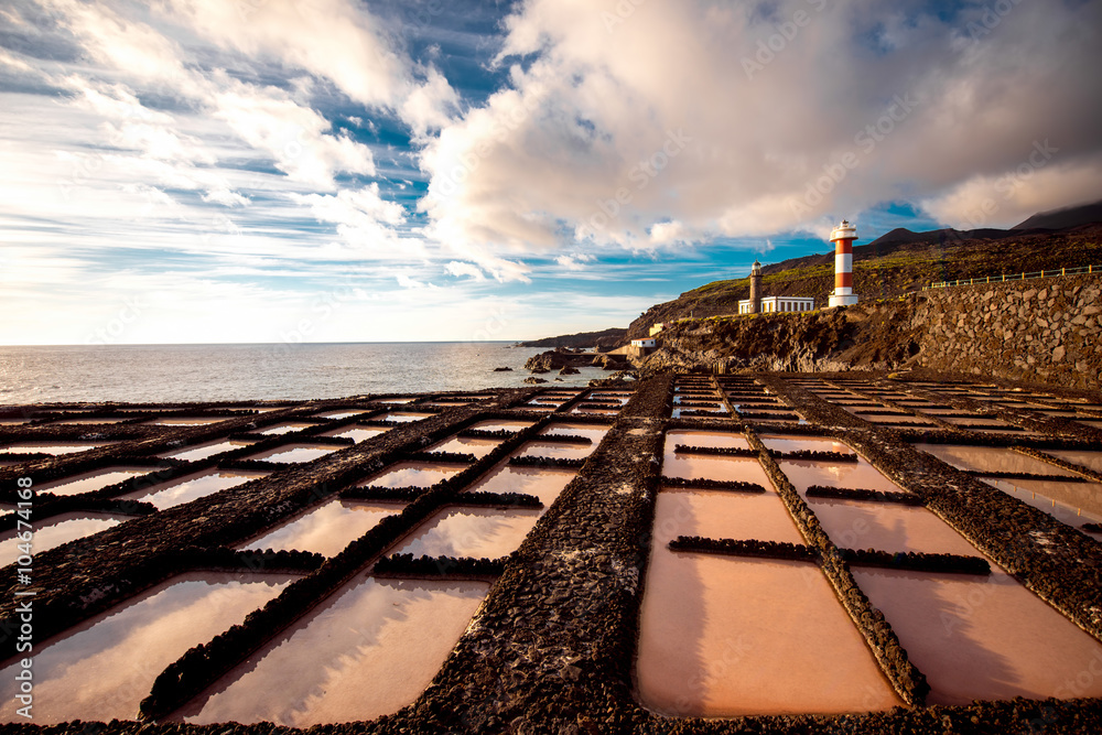 Volcanic pools on the salt manufacturing Fuencaliente with lighthouse and mountains on the backgroun