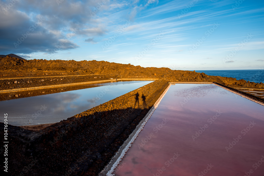 Volcanic pool on the salt manufaturing with pink salt water and sky reflection on La Palma island