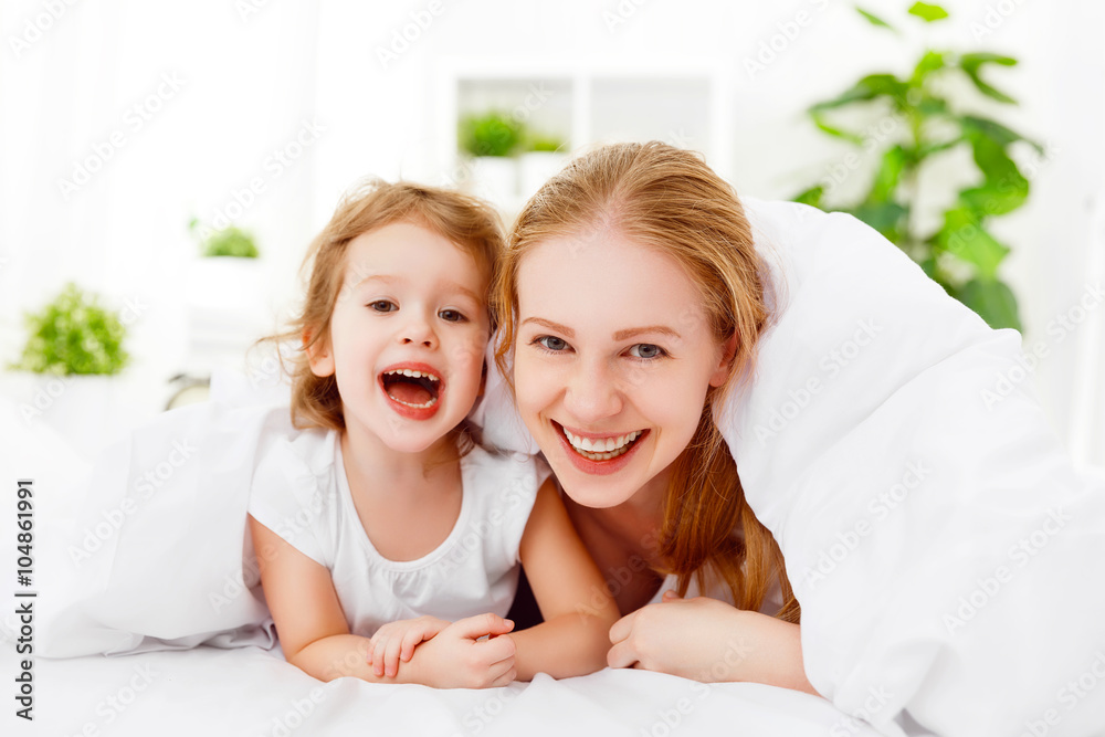 happy family mother and child playing and laughing in bed