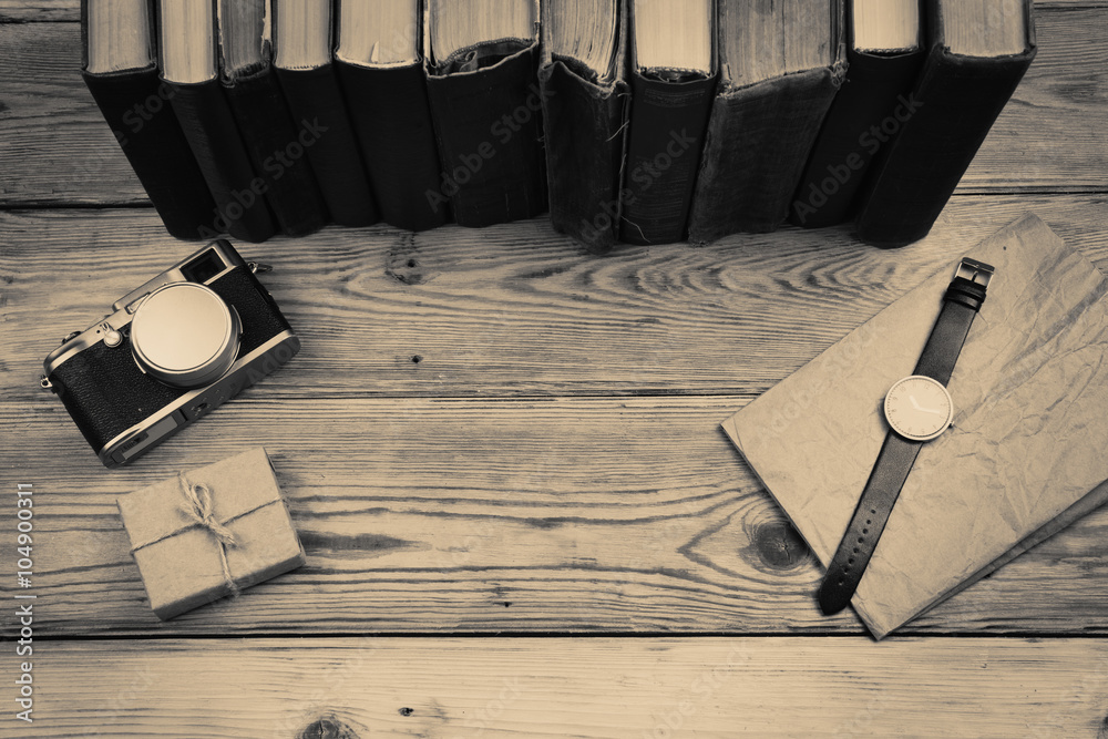 Top view on wooden desktop with books, camera, watch and gift bo