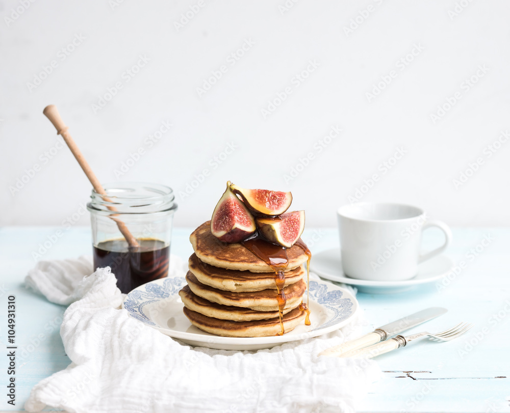 Pancake tower with fresh figs and honey on a rustic plate. White background