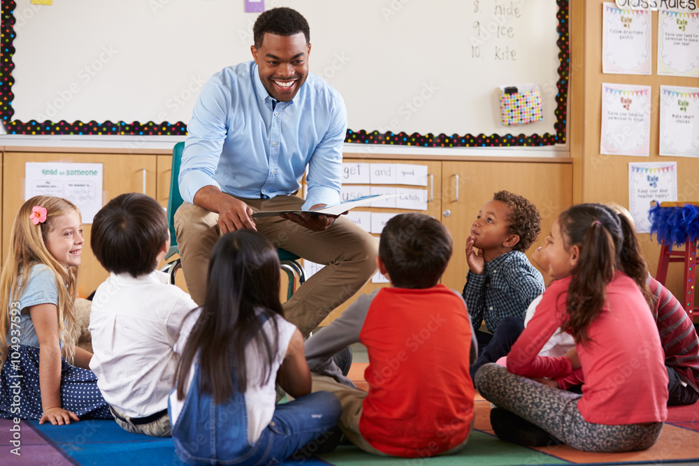 Elementary school kids sitting around teacher in a classroom