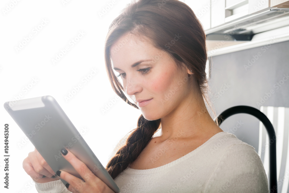 Woman using tablet to cook in home kitchen