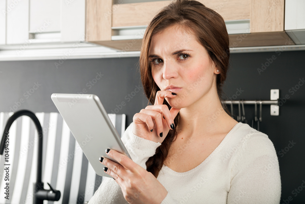 Woman using tablet to cook in home kitchen