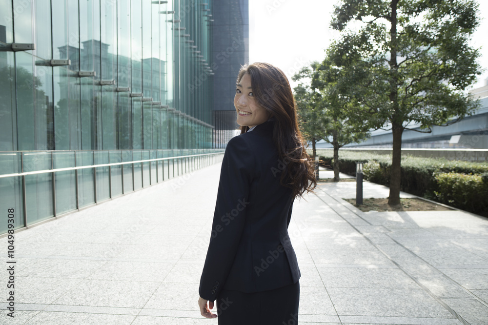 Woman wearing a business suit is turned around with a smile