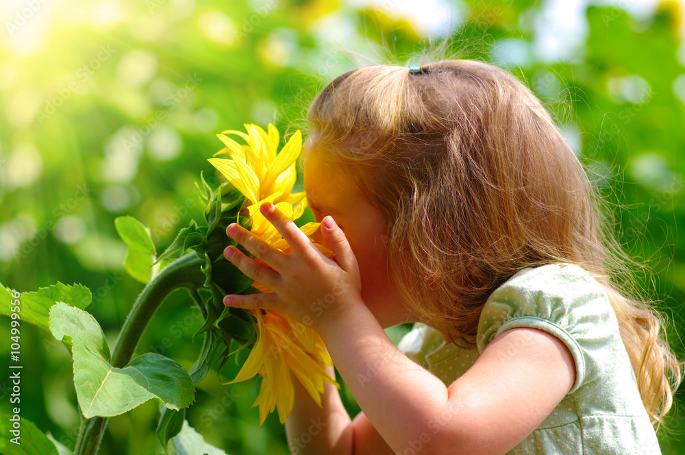 little girl smelling a sunflower