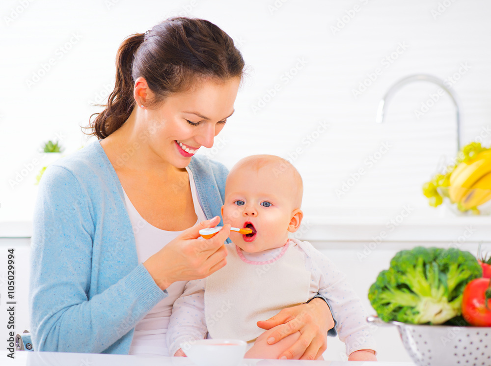 Mother feeding her baby girl with a spoon