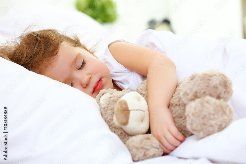 child little girl sleeps in the bed with teddy bear