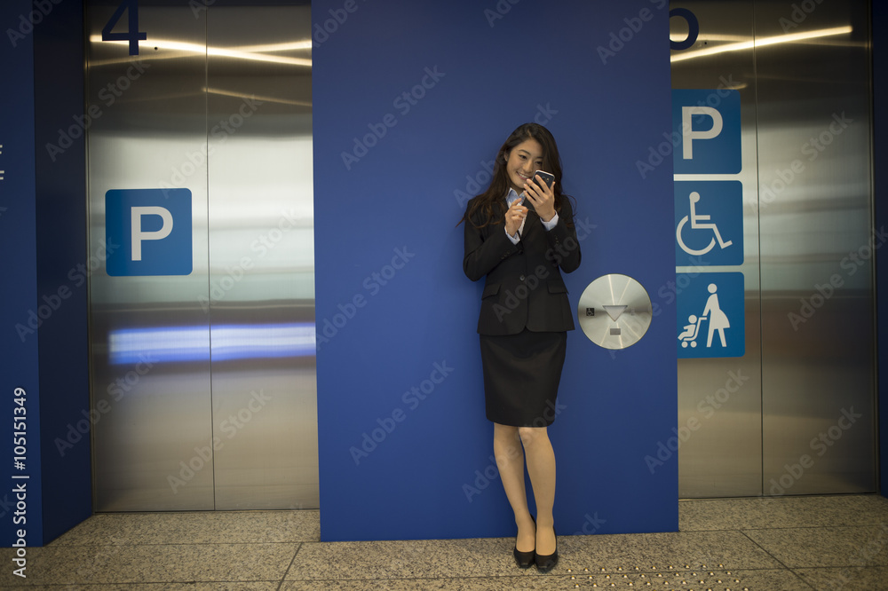 
Women who are using the smartphone in front of the elevator