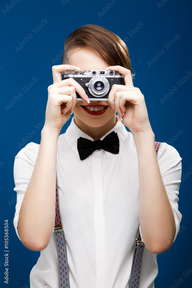 Happy girl holding retro camera in front of her face