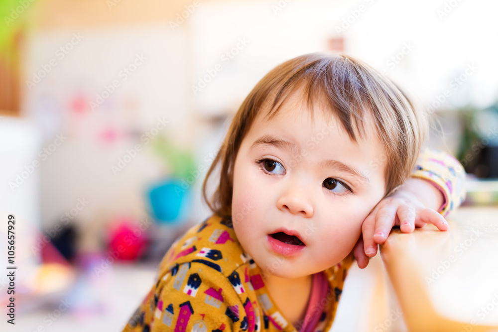 Toddler girl leaning against table