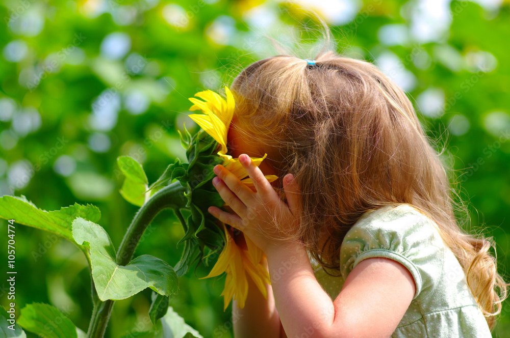 little girl smelling a sunflower