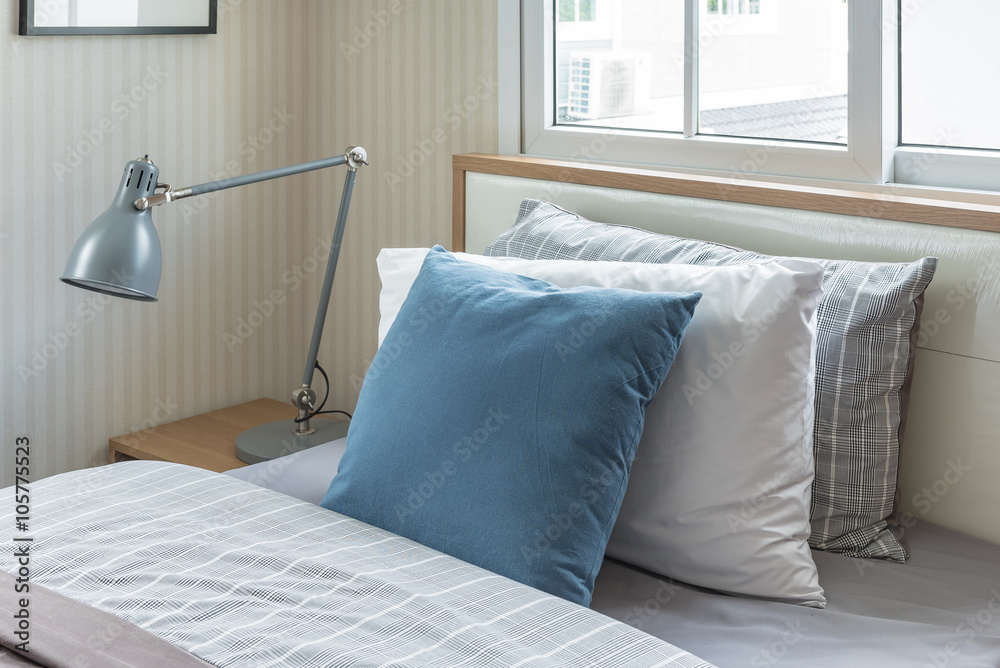 blue pillow on single bed with modern grey lamp in modern bedroo