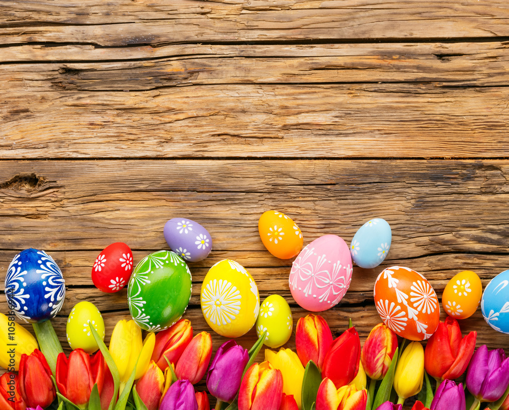 Easter eggs and tulips on wooden background