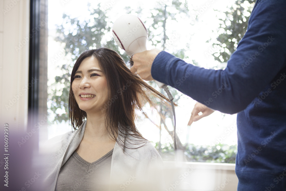 Beautician is dry the long hair of woman